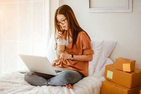 Young woman asian work from home talking with customers to sell products online and delivery for customer. Business owner, SME, shipping, work from home(WFH), freelance, Start up concept.の写真素材