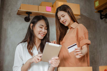 Young woman asian work from home online marketing currently ordering products for sale and delivery for customer. Business owner, SME, shipping, work from home(WFH), freelance, Start up concept.の写真素材