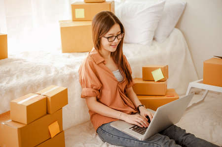Young woman asian work from home talking with customers to sell products online and delivery for customer. Business owner, SME, shipping, work from home(WFH), freelance, Start up concept.の写真素材