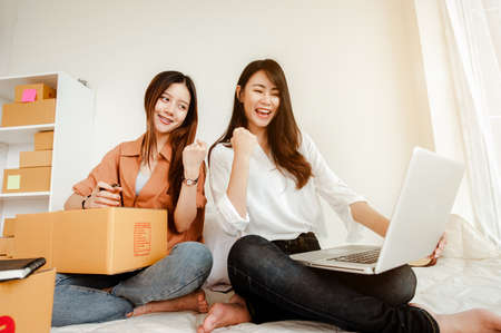 Young woman asian work from home talking with customers to sell products online and delivery for customer. Business owner, SME, shipping, work from home(WFH), freelance, Start up concept.の写真素材