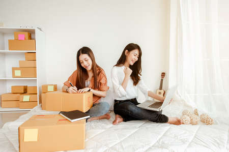Young woman asian work from home talking with customers to sell products online and delivery for customer. Business owner, SME, shipping, work from home(WFH), freelance, Start up concept.の写真素材
