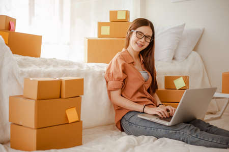 Young woman asian work from home talking with customers to sell products online and delivery for customer. Business owner, SME, shipping, work from home(WFH), freelance, Start up concept.の写真素材