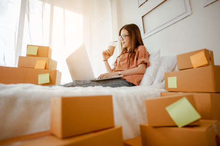 Young woman asian work from home talking with customers to sell products online and delivery for customer. Business owner, SME, shipping, work from home(WFH), freelance, Start up concept.の写真素材