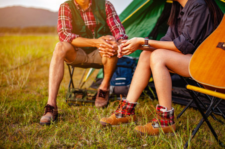 Male and female asian travelers are sitting and enjoying a drink after a set up outdoor tent in the forest path autumn season. Hiking, hiker, team, forest, camping , activity concept.の写真素材