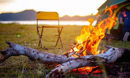 Camping bonfire surrounded by team of asian climbers hiker, they are playing music together in the forest path autumn season. Hiking, hiker, team, forest, camping , activity concept.の写真素材