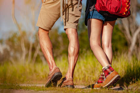 Young couple asian in a wide field is walking on foot to explore the forest as a holiday activity in the forest path autumn season. Hiking, hiker, team, forest, camping, activity concept.の写真素材