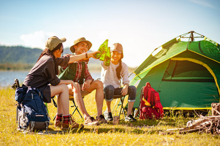 Team of asian climbers hiker are sitting and enjoying a drink after a set up outdoor tent in the forest path autumn season. Hiking, hiker, team, forest, camping , activity concept.の写真素材