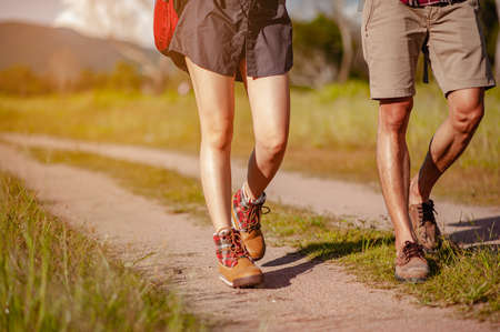 Young couple asian in a wide field is walking on foot to explore the forest as a holiday activity in the forest path autumn season. Hiking, hiker, team, forest, camping, activity concept.の写真素材