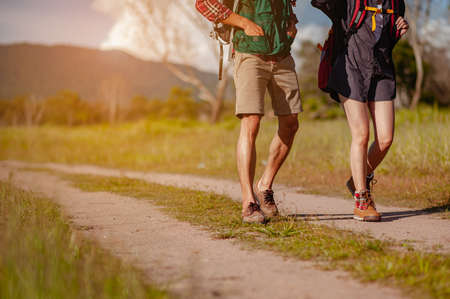 Young couple asian in a wide field is walking on foot to explore the forest as a holiday activity in the forest path autumn season. Hiking, hiker, team, forest, camping, activity concept.の写真素材