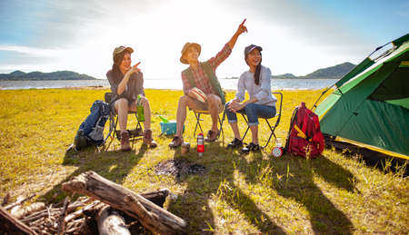 Team of asian climbers hiker are sitting and enjoying a drink after a set up outdoor tent in the forest path autumn season. Hiking, hiker, team, forest, camping , activity concept.の写真素材
