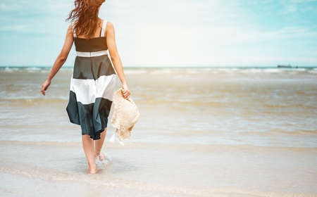 Happy asian women with holding hat walking barefoot to receive the wind and enjoy life on the beach vacation. beach, summer, liftstyle, positive mood, travel, relax concept.の写真素材
