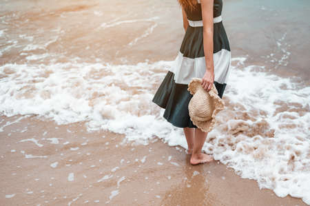 Happy asian women with holding hat stand to receive the wind and enjoy life on the beach vacation. beach, summer, liftstyle, positive mood, travel, relax concept.の写真素材