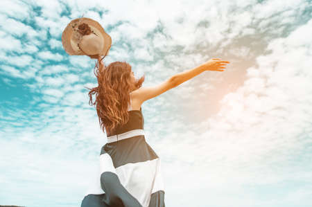 Happy asian women with holding hat stand to receive the wind and enjoy life on the beach vacation. beach, summer, liftstyle, positive mood, travel, relax concept.の写真素材
