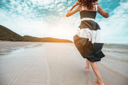 Happy asian women with holding hat walking barefoot to receive the wind and enjoy life on the beach vacation. beach, summer, liftstyle, positive mood, travel, relax concept.の写真素材