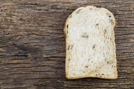 Whole wheat bread slice have rice grain isolated on wood background close up, top view, copy space,...