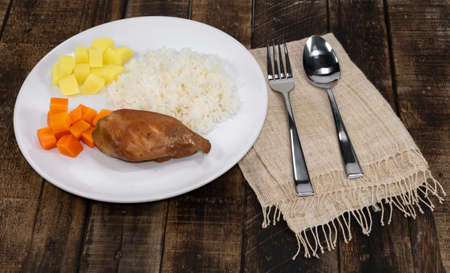 Rice dish with fried chicken breast have vegetable carrot potato in plate isolated on wood background close up, top view, healthy food and drink concept.の写真素材