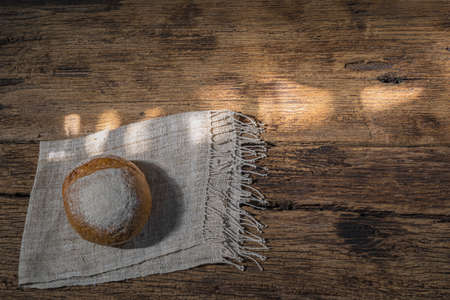 round bread isolated on wood background, gold rustic crusty bun have sun highlight, top view, food...