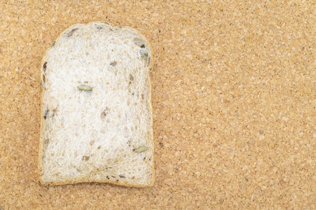 Whole wheat bread slice have rice grain isolated on wood background close up, top view, copy space,...
