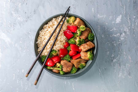 Rice dish chicken fried and vegetable broccoli pepper in bowl isolated on grey background close up, top view, healthy food and drink concept.の写真素材