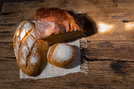 different bread rye round baguette isolated on wood background, gold rustic crusty bun have sun...