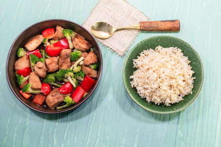 Rice dish chicken fried and vegetable broccoli pepper in bowl isolated on green background close up, top view, healthy food and drink concept.の写真素材