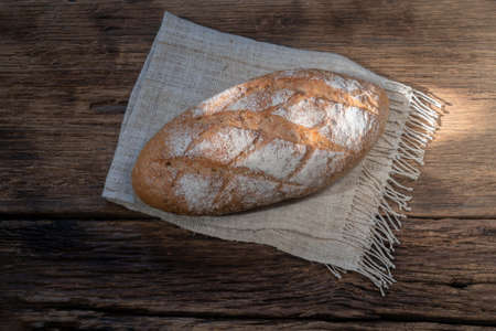 baguette bread isolated on wood background, gold rustic crusty bun have sun highlight, top view, food and drink concept.の写真素材