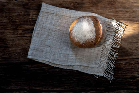 round bread isolated on wood background, gold rustic crusty bun have sun highlight, top view, food...
