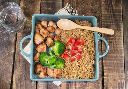 Fried rice dish with chicken breast has vegetable broccoli pepper in tray isolated on wood background close up, top view, healthy food and drink concept.の写真素材