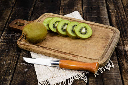 Kiwi fruit slice in cutting board have knife isolated on wood background closeup, health food and drink concept.の写真素材