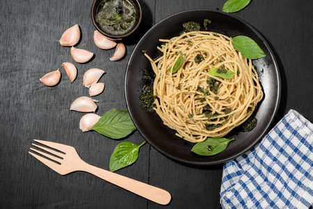 Pasta with pesto sauce in plate on black wood background close up, top view, Italian food concept.の写真素材