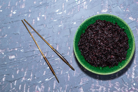 Black rice in bowl isolated on grey background has chopsticks close up, top view, healthy food and drink concept.の写真素材