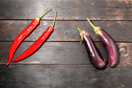 Red pepper chili and eggplant isolated on dark wood background close up, top view, food concept.の写真素材