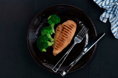 Grill chicken and broccoli in plate on black wood background, top view healthy food concept.の写真素材