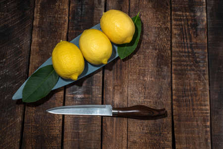 Lemon pile in bowl has leaves on wood background close up, top view, bio food concept.の写真素材