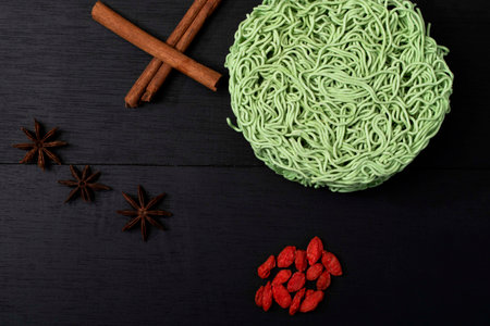 Green instant noodle on black wood background has cinnamon anise wolfberry, top view, Asian food concept.の写真素材