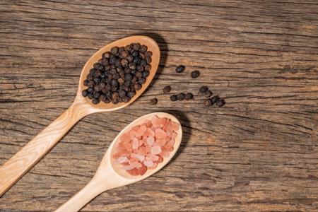 Pink himalayan salt and pepper in spoon on wood background, top view, copy space, condiment food concept.の写真素材