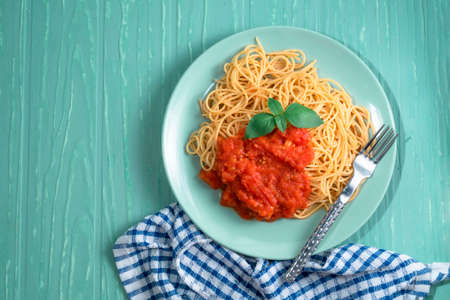 Pasta spaghetti with tomato sauce in green plate on green background, top view, Italian food concept.の写真素材