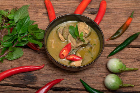 Green chicken curry has eggplant chill basil in bowl on wood background, top view, Asian food conceptの写真素材