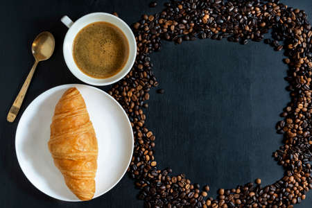 Espresso coffee and croissant in plate on isolated wood table background close up, top view,...