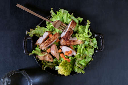 Chicken salad in bowl on black wood background close up, top view, healthy food concept.の写真素材