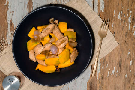 Stir fried chicken add pumpkin onion in plate on wood background, top view, food and drink concept.の写真素材