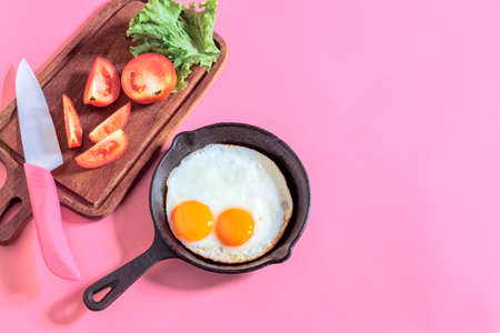 Fried egg in skillet pan isolated on pink background close up, top view, breakfast food concept.の写真素材