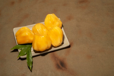 Jackfruit in plate has leaf on wood background close up top view, healthy fruit concept.