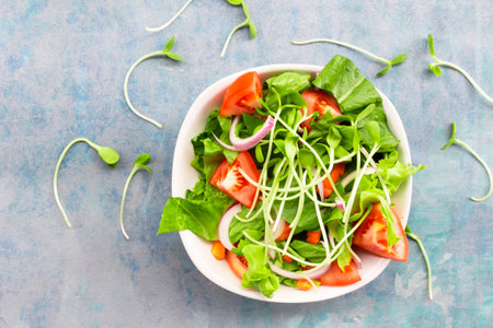 Leave lettuce salad has tomato sunflower sprout in bowl isolated on blue wood background close up, top view, healthy vegetable food concept.の写真素材