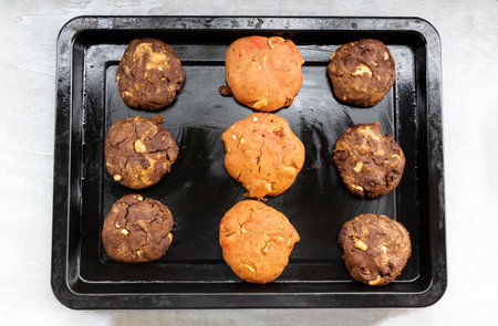 Chocolate cookies and strawberry has cashew nuts raisin in black tray on white wood background close...