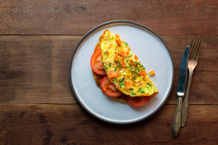 Omelet has tomato in plate isolated on wood background, top view, healthy breakfast food concept.の写真素材