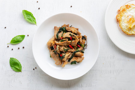 Stir fried basil with pork and fried egg on white table close up, top view, Thai food concept.の写真素材
