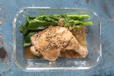 Steamed chicken with herbs in lunch box on blue wood background top view, healthy food concept.の写真素材