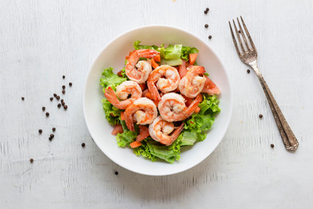 Shrimp salad lettuce carrot tomato in bowl on wood background top view, healthy food concept.の写真素材