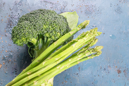 Fresh broccoli asparagus vegetables on blue wood background copy space, top view, healthy food concept.の写真素材